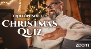 a man sitting in front of a Christmas tree using a laptop