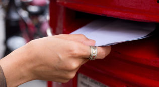 image of woman's hand posting a letter